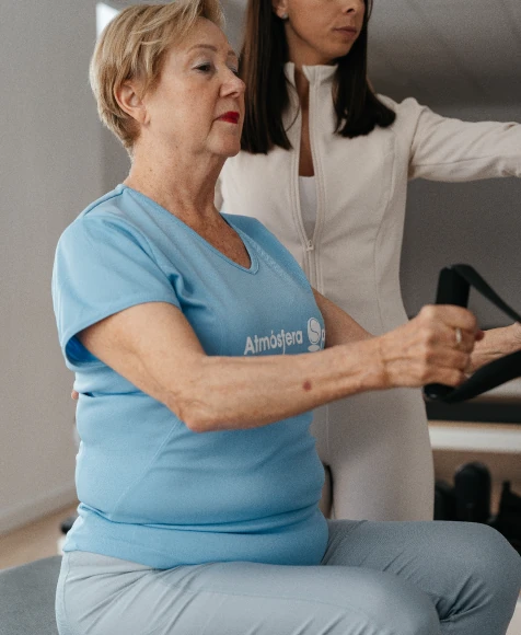 Instructora de ELIX Pilates guiando a una alumna sénior con correas