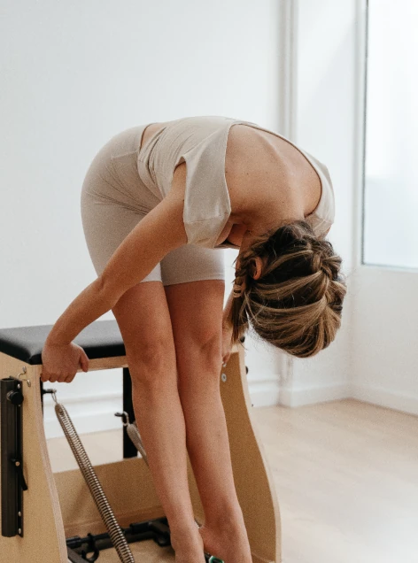 Alumna realizando flexión de columna sobre la Wunda Chair en ELIX Pilates